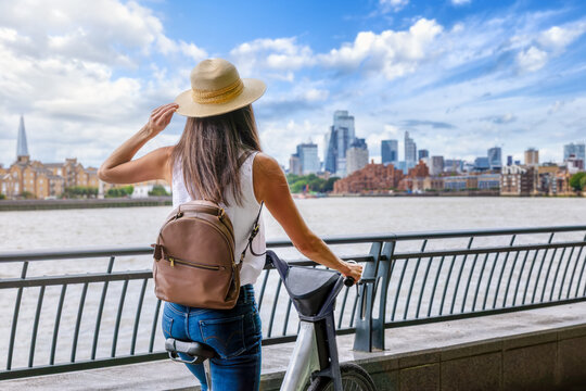 A tourist woman explores the City of London on a bicycle during a sunny summer day in England