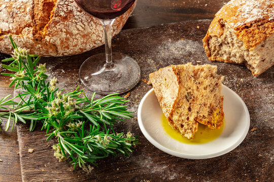 Close-up of a rustic, torn piece of homemade artisan sourdough bread with red wine