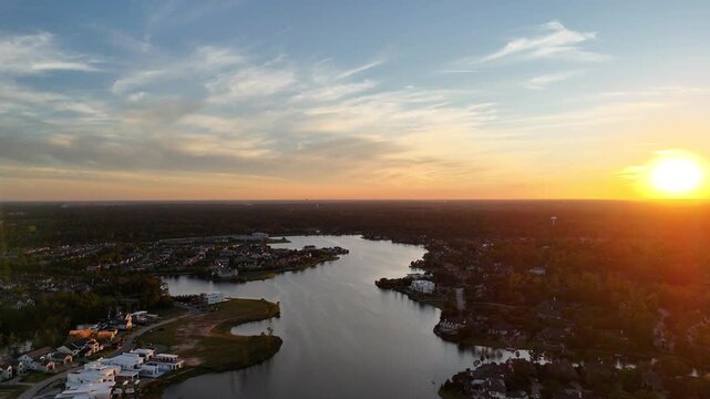 Aerial view of luxury houses in Houston, Woodlands by the lake with dramatic sky by sunset in Texas, United States
