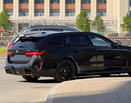BMW M5 VII G90 black color drive on street on sunny summer day. Exterior of a black car. Black sport sedan BMW M5 VII G90 on drive on road. Germany sport car. 