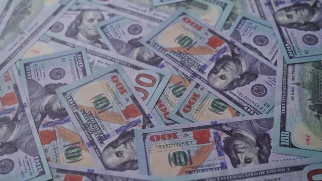 Background of one hundred US dollar bills scattered randomly.