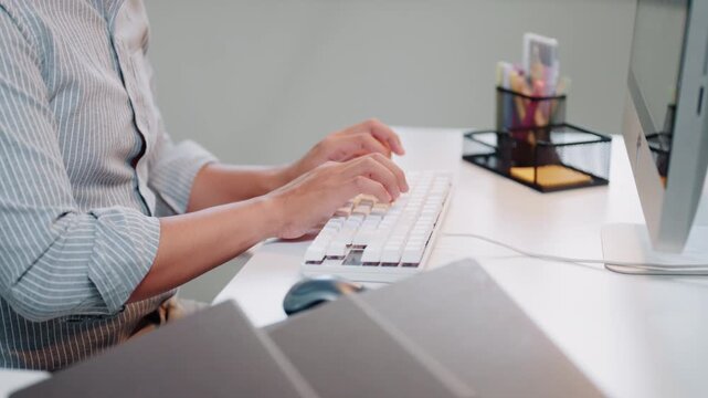 Person Typing on White Keyboard at Clean Modern Office Desk with Computer and Stationery