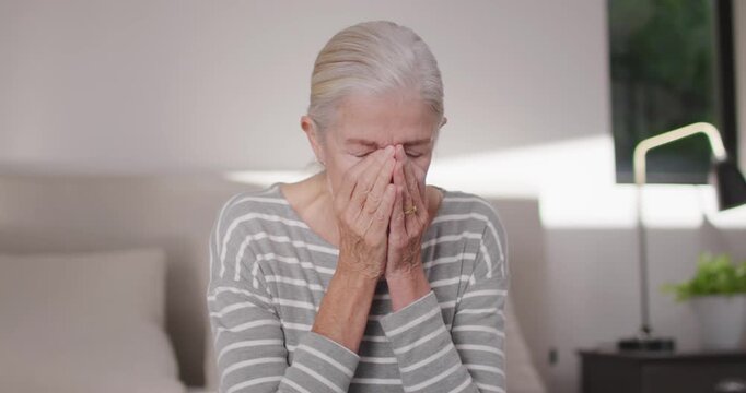 Starting with hands pressing face, Senior woman nodding and pausing at home with nightstand lamp