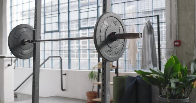Camera is panning and lowering to showcase mounted barbell with large right plate in loft space