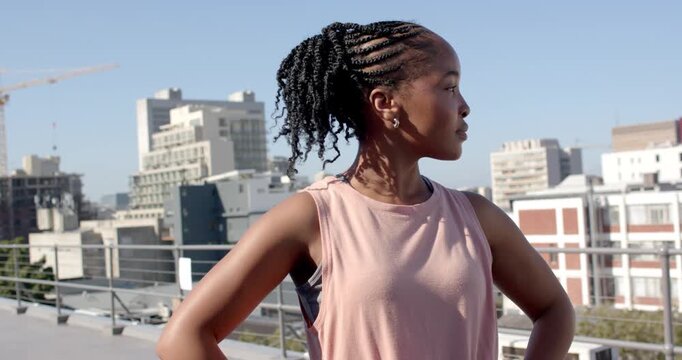 African American woman turning front on roof, camera zooming, crossing arms, smiling for portrait