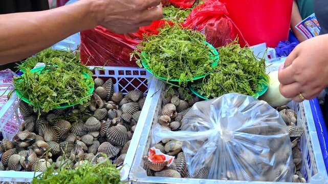 MAKASSAR, INDONESIA - JULY 5, 2026: Close-up of a cash transaction at a traditional seafood market stall, with a buyer handing over Indonesian Rupiah banknotes to a seller.