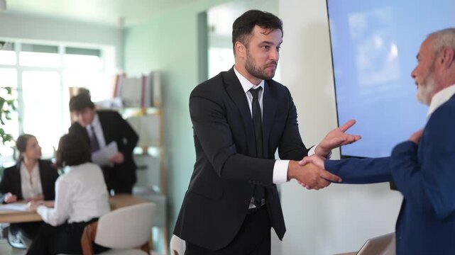  Adult male bank manager shakes hand with elderly man client during business meeting