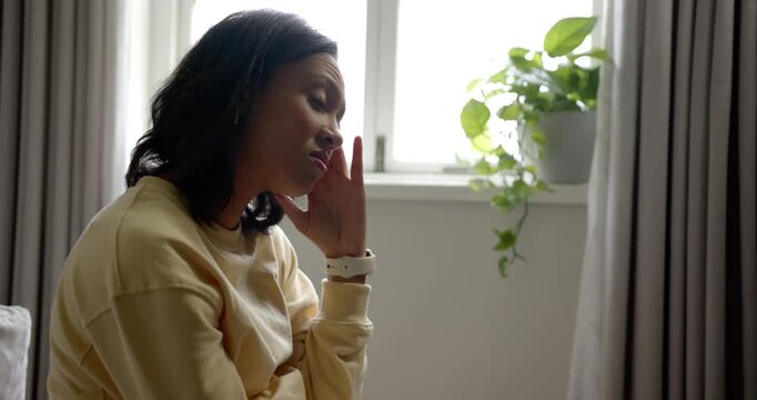 African American woman squinting from window on couch raising hand to temple leaning, copy space