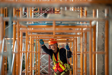 Fototapeta na wymiar Dedicated construction worker engineering on a building site under scaffolding framework with safety gear