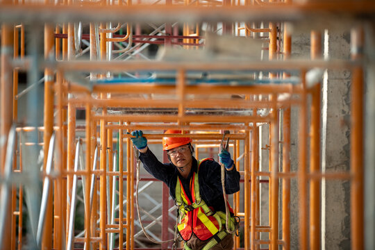 Dedicated construction worker engineering on a building site under scaffolding framework with safety gear