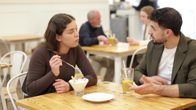 Girl in cafe spend time with guy, has nice conversation, work or romantic meeting dating. Cozy atmosphere of cafe, meeting place for friend, business partner, relative