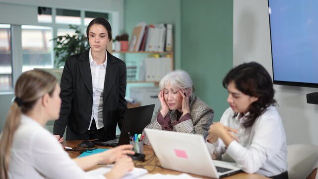 Angry young female manager standing and scolding colleagues during a stressful corporate meeting. High quality 4k footage