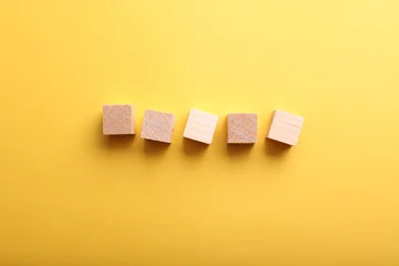 Five blank wooden cubes on yellow paper background © splitov27