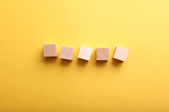 Five blank wooden cubes on yellow paper background