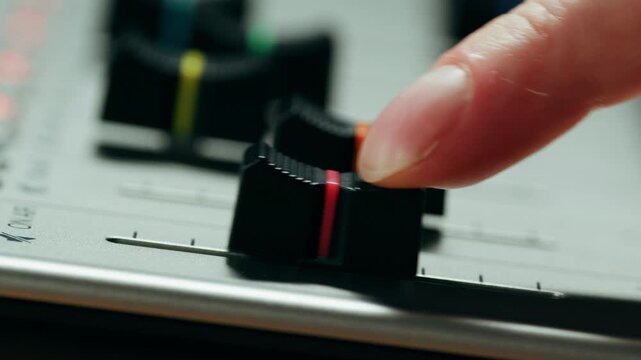 Music studio close up, Close up hands shot of sound engineer using mixing console, remote control for adjusting sound, audio mixer. Musician creates music, makes remix for DJ set. Sound
