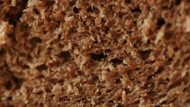 Black rye bread close up, cutting with knife dark brown sliced loaf, borodinsky slavic food, square slices with coriander on white background, baker with tasty healthy fresh bread.