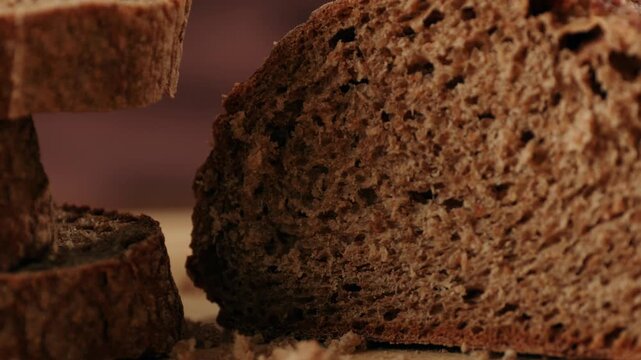 Black rye bread close up, cutting with knife dark brown sliced loaf, borodinsky slavic food, square slices with coriander on white background, baker with tasty healthy fresh bread.