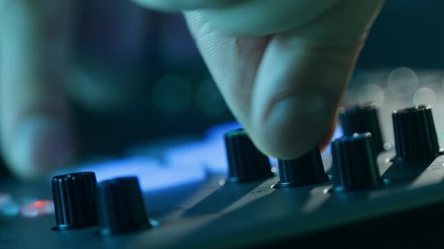 Music studio close up, Close up hands shot of sound engineer using mixing console, remote control for adjusting sound, audio mixer. Musician creates music, makes remix for DJ set. Sound