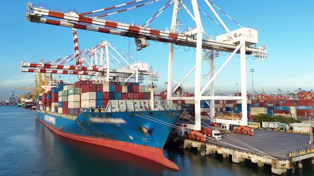 cargo container ship docked at a busy commercial port terminal with massive gantry cranes loading freight for global maritime logistics and international trade supply chain.	