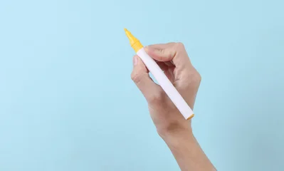 Woman's hand draws with yellow felt-tip pen on a blue background © splitov27