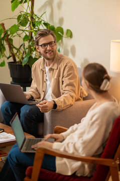 Young man and woman working from home and looking contented