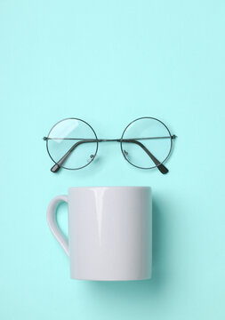 Ceramic cup and eyeglasses on a blue background