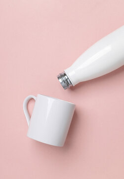 Mockup of white empty ceramic cup and thermos bottle on pink background