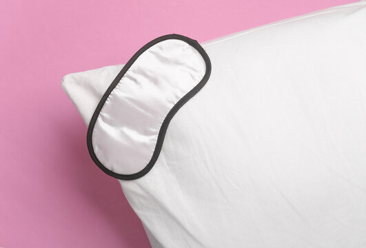 Sleeping mask with pillow on a pink background. Healthy sleep concept