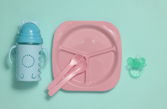 Set of plastic dishes for feeding baby on blue background. Top view