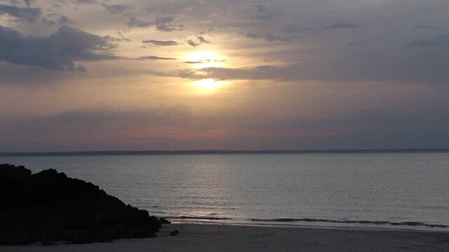 Dramatic evening red sky with the sun rays crossing the clouds. Harmony of meditation near the beautiful sea waves of Normandie and Bretagne. The golden and blue hour of the sunset.