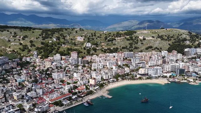 Saranda, Albania. Aerial 4K panoramic drone view of the Ionian Sea, port, boats and Mediterranean urban architecture. Majestic view of the resort town and its beaches.