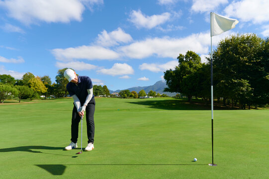 Man putting golf ball on green golf course