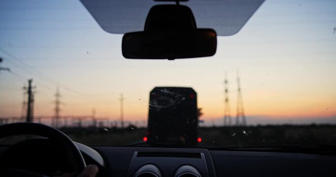 POV video from inside a vehicle driving down a country road at dusk, trailing a large bus silhouette with glowing taillights under a sunset sky with a cinematic shallow depth of field