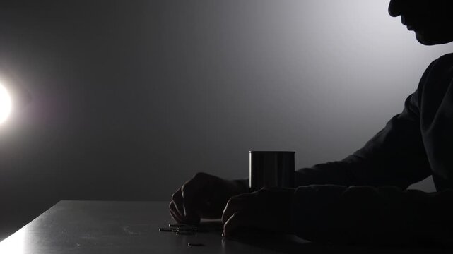 Person's hand emptying a metal can, revealing a small amount of cash and coins on a dark table, highlighting themes of financial struggle, bankruptcy, and poverty awareness
