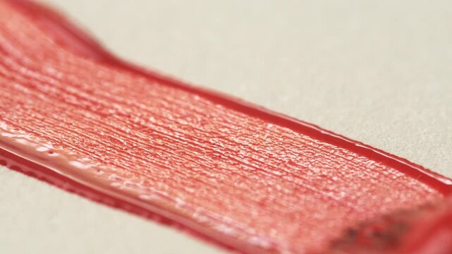A close-up of a brush leaving a red line on white paper. The process of brush movement and paint texture during the creation of a drawing. Hobbies and leisure concepts