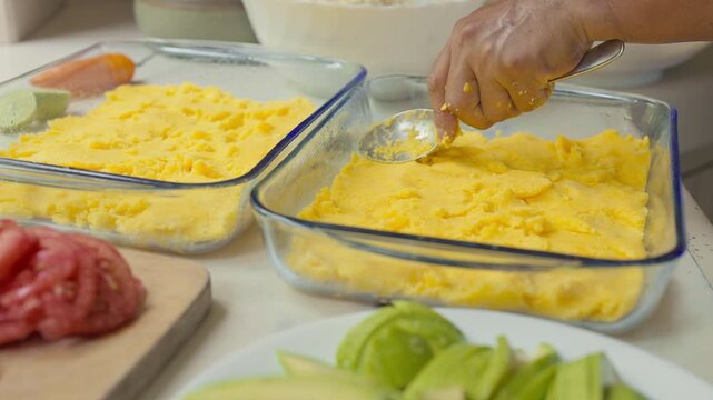 Preparing Peruvian Causa Rellena Layers in Glass Baking Dishes
