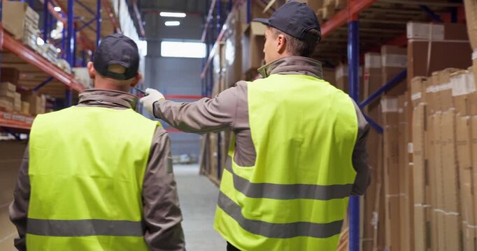 Warehouse workers review shelves and boxes for delivery. A supervisor is pointing out logistics tasks and inventory checks for safety. Strong teamwork ensures efficient warehouse logistics.