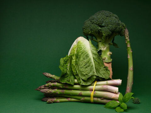 Still life with green vegetables arranged on a dark green surface
