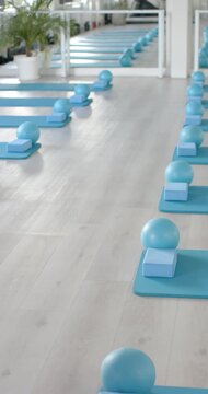 Vertical video: Camera is gliding forward, revealing teal mats and foam blocks in studio for class