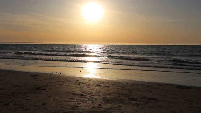 Dramatic evening red sky with the sun rays crossing the clouds. Harmony of meditation near the beautiful sea waves of Normandie and Bretagne. The golden and blue hour of the sunset.