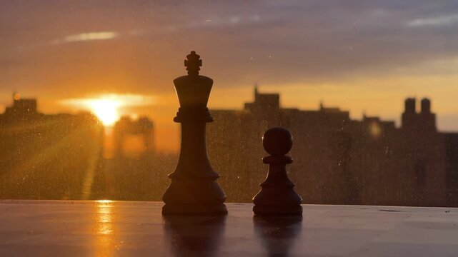 Close-up of brown wooden chess pieces on a board with a clear blue sky background.
