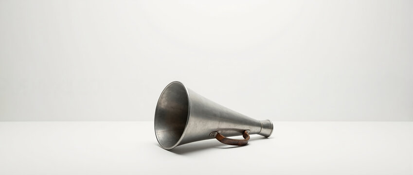 Vintage metal megaphone with leather handle on white background. Antique tin bullhorn for director or coach. Retro communication concept