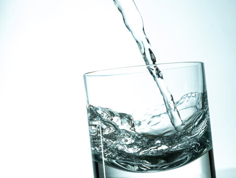 Pouring fresh water in a glass on a bright background