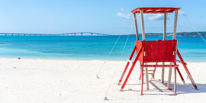 Panoramic view of Miyakojima sunset beach view with a red lifeguard tower and Irabu bridge view in background in Miyako island Okinawa Japan