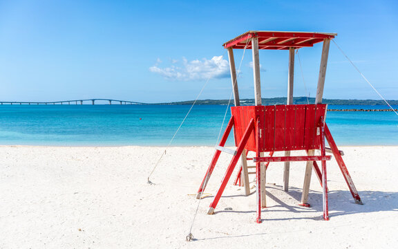 Miyakojima sunset beach view with a red lifeguard tower on white sand an blue water Irabu bridge view in background in Miyako island Okinawa Japan