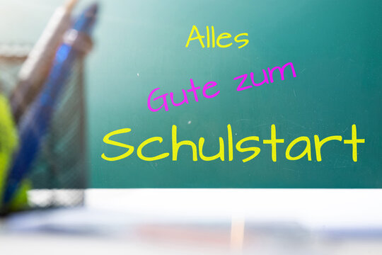 Tafel mit hinzugef&uuml;gtem Text ALLES GUTE ZUM SCHULSTART hinter einem Schreibtisch