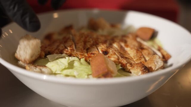 Professional chef preparing a delicious chicken caesar salad with lettuce, grilled chicken and croutons, fa01