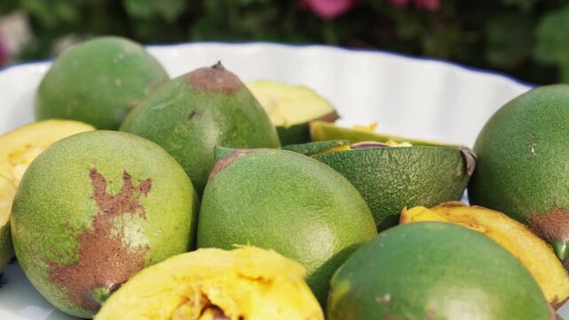 Fresh Whole and Sliced Peruvian Lucuma Fruit in a White Bowl