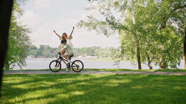 Mother celebrates son riding bicycle alone against calm river
