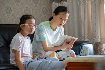 Fototapeta premium The mother helps her daughter with homework